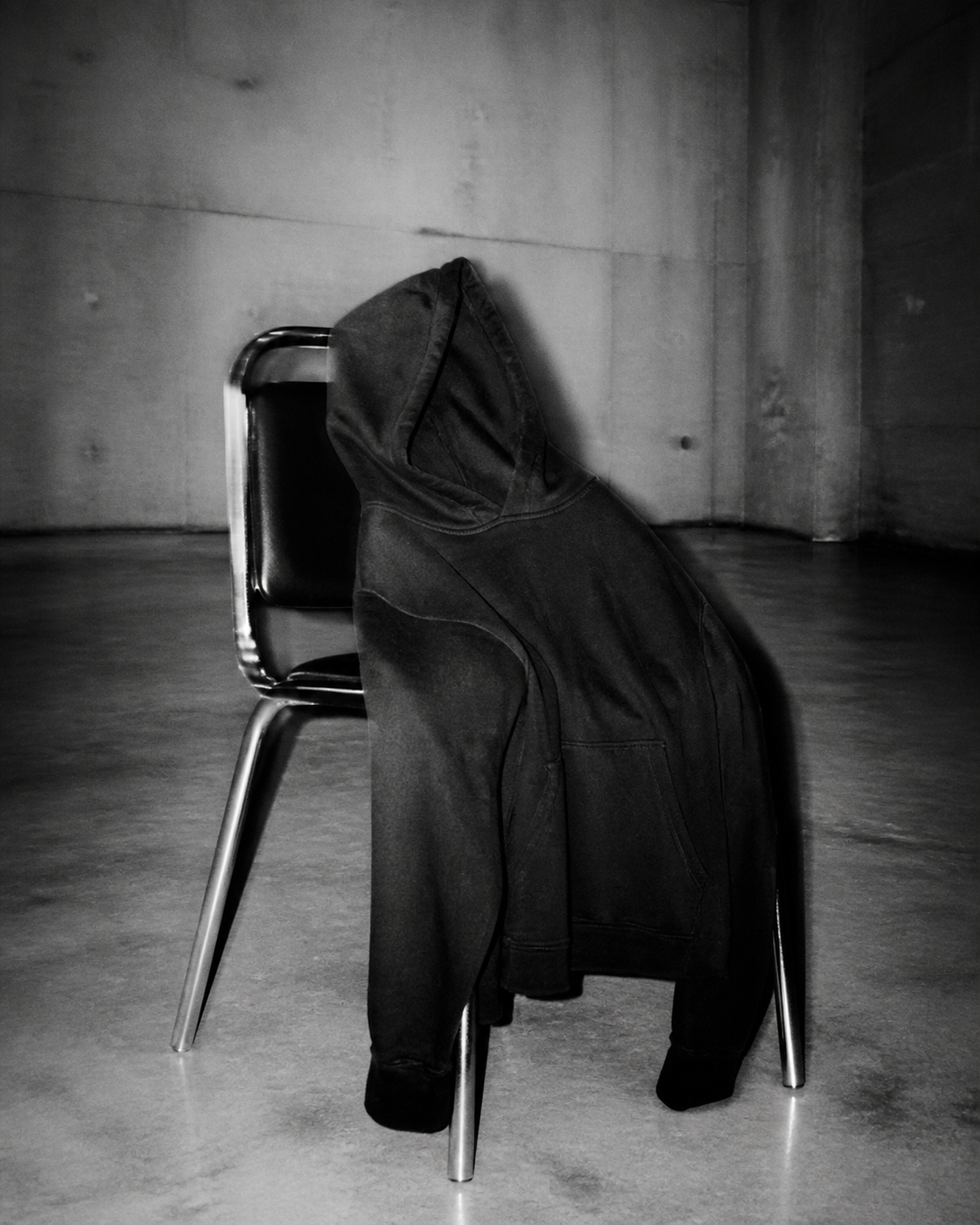 Washed dark hoodie in an empty concrete room